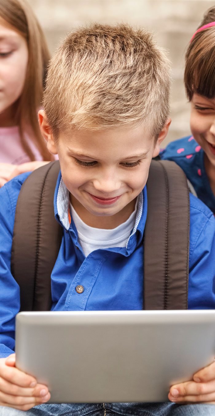 Child smiling while using a tablet outdoors. Child smiling while using a tablet outdoors.