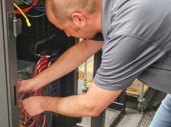 Man organizing cables in a server rack.