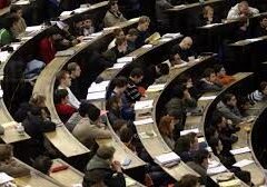 Students in a large lecture hall taking notes and listening attentively.