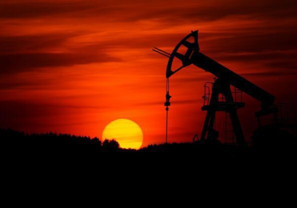 Oil pumpjack silhouette against a red sunset.