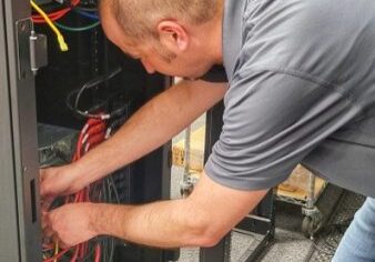 Man organizing cables in a server rack.