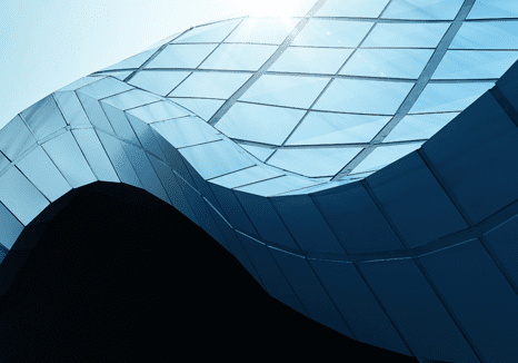 Curved glass building with sunlight reflection.